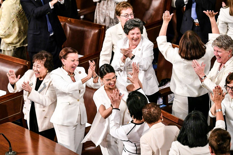 The congresswomen, all dressed in white, cheer and clap.